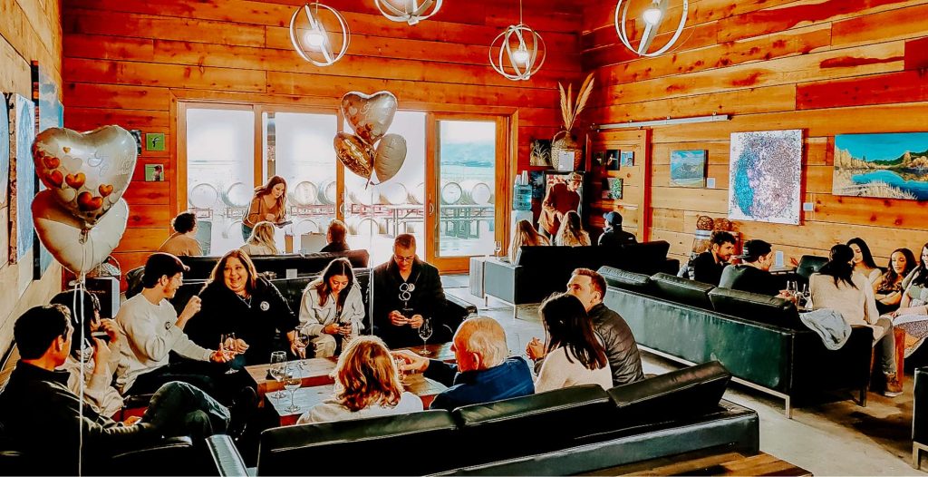 A gathering space at Darcie Kent Vineyard in the Big Barn with different groups of people celebrating with wine tasting