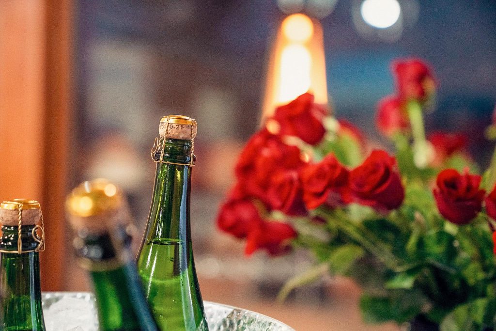 Sparkling wine bottles in an ice bucket with red roses blurred in the background at Darcie Kent Estate Winery in Livermore, CA
